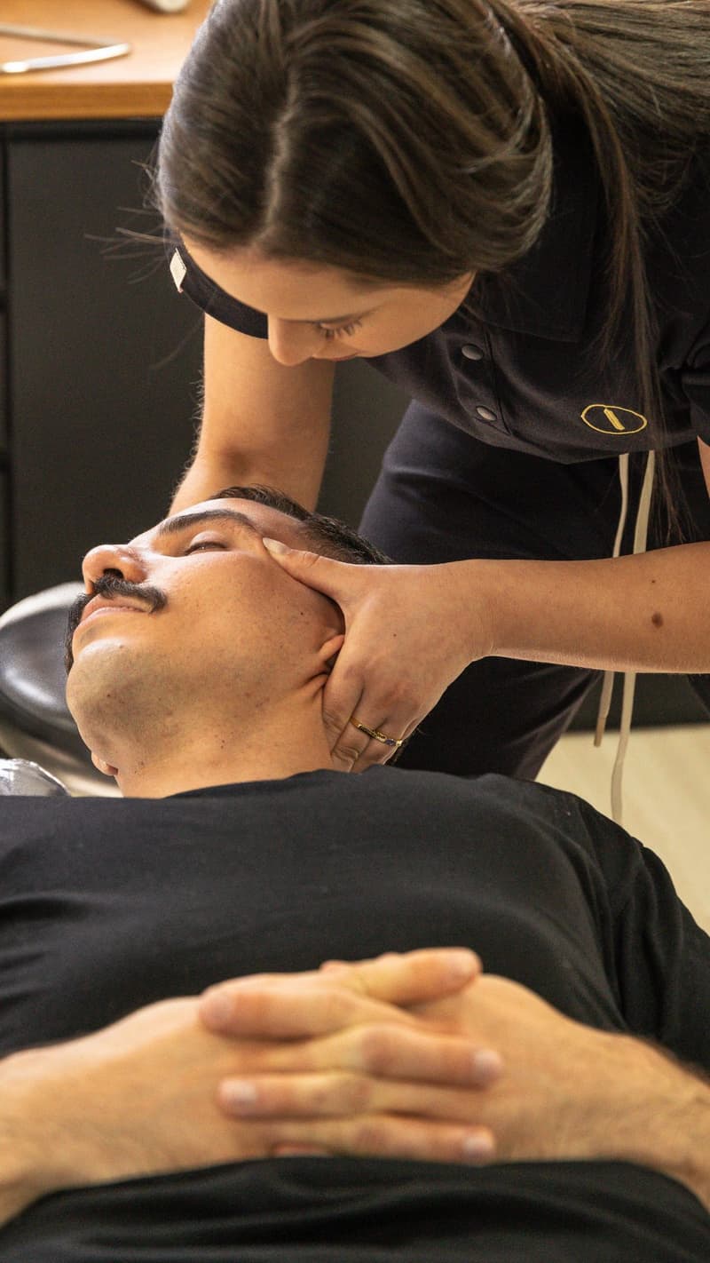 Quiropraxista da Axium realizando ajuste cervical em paciente deitado